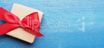 Gift box with a red bow on blue wood