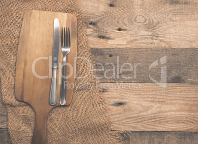 Old flatware with cutting board on wood