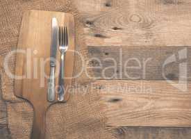 Old flatware with cutting board on wood