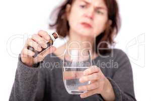Woman with medicine bottle and water glass