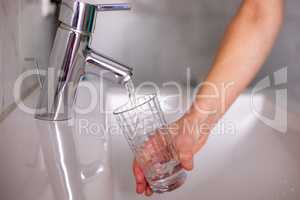 Hand with glass under running tap
