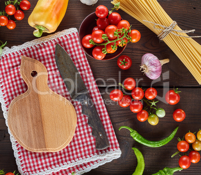 cutting board with a knife and fresh red cherry tomatoes