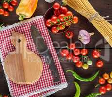 cutting board with a knife and fresh red cherry tomatoes