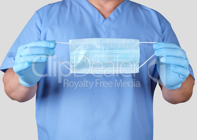 doctor in blue uniform and latex gloves holding a medical mask