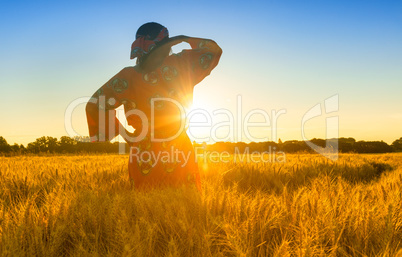 African woman in traditional clothes standing in a field of crop