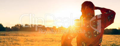 African woman in traditional clothes in a field of crops at suns