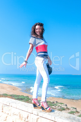 Cheerful girl in white jeans is balancing on the parapet