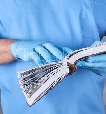 doctor in blue uniform holds an open book in his hands