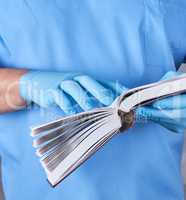 doctor in blue uniform holds an open book in his hands