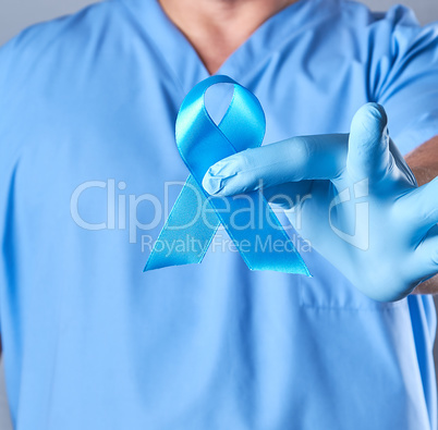 doctor in uniform and latex gloves holding a blue ribbon