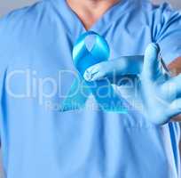 doctor in uniform and latex gloves holding a blue ribbon