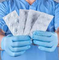 doctor in blue latex gloves holds pills