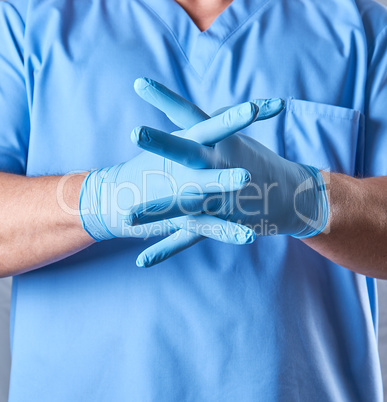 doctor in a blue uniform puts on sterile latex gloves