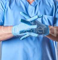 doctor in a blue uniform puts on sterile latex gloves