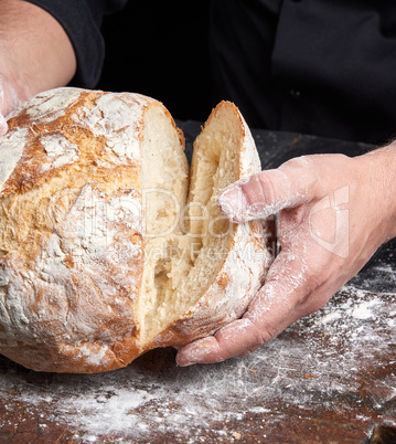 cook in a black tunic holds fresh baked bread