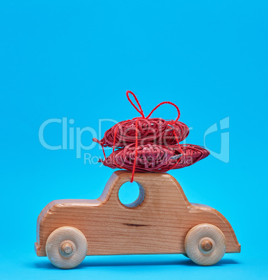 small wooden children's car carries a wicker red heart