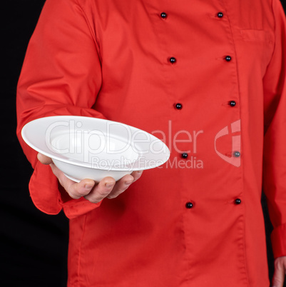 chef in red uniform holds in his right hand a round white plate