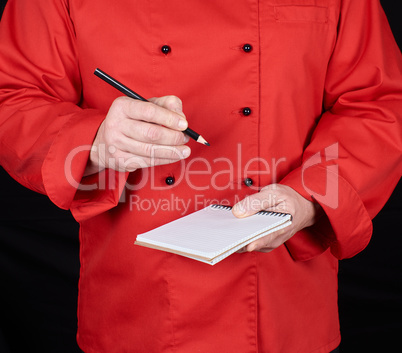 chef in red uniform  holding a blank notebook and a black wooden