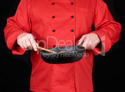 cook in red uniform holding an empty black frying pan