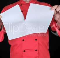 chef in red uniform holding a blank white sheet and tearing it i