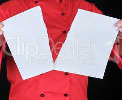 man in a red uniform holds a white sheet of paper torn in half