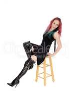 Woman sitting in long boots and dress on chair