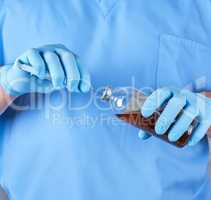 doctor in blue uniform holds a syringe and a glass bottle