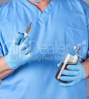 doctor in blue uniform and latex sterile gloves holding a syring