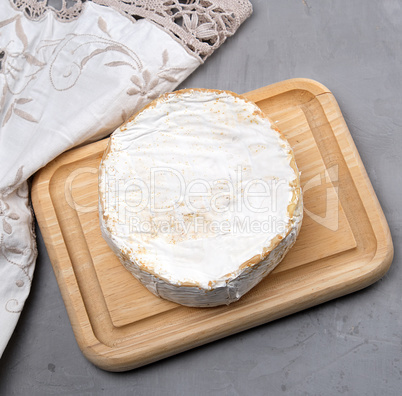 round piece of brie cheese on a wooden board