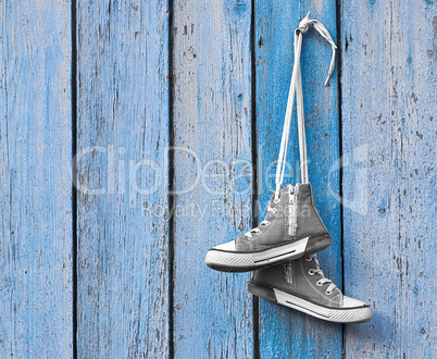 pair of used textile shoes hang on a blue background