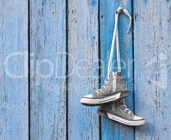 pair of used textile shoes hang on a blue background