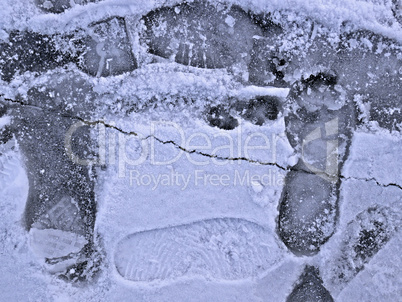 Frozen pond surface with footprints close-up