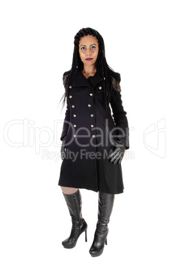 Young woman standing in black coat and boots