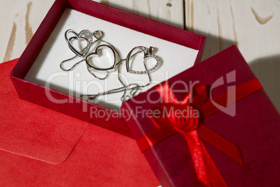 Closeup of silver heart pendants in a red gift box and a red env
