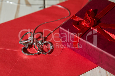 Closeup of silver heart pendants on a red envelope and gift box