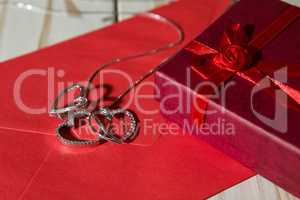 Closeup of silver heart pendants on a red envelope and gift box