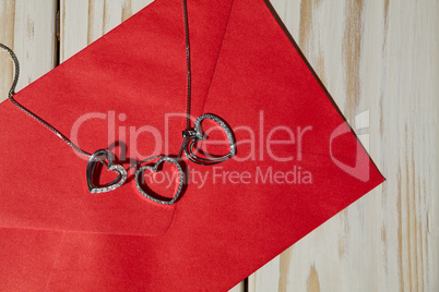 Closeup of silver heart pendants on a red envelope