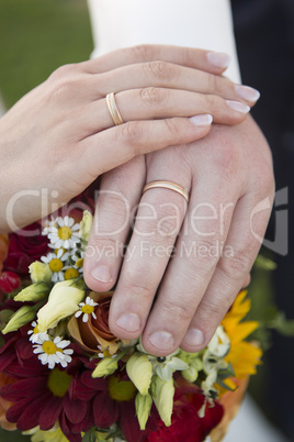 Hands of bride and groom with flower bouquet