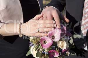 Hands of bride and groom with flower bouquet