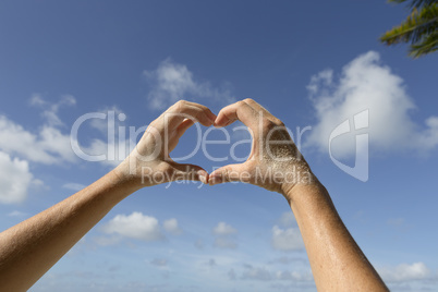 Female hands in front of blue sunny sky, vacation concept