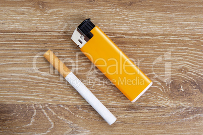 Cigarette and orange lighter on a wooden background