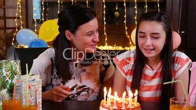 Happy teen girl and mother with birthday cake at anniversary party