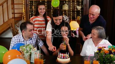 Mother lighting candles on her daughter birthday cake at party