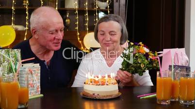Happy senior couple blowing candles at birthday party