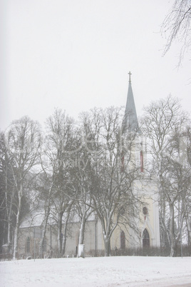 Winter landscape with snow covered church and trees.