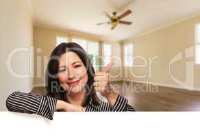 Hispanic Woman with Thumbs Up In Empty Room of House