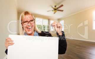 Attractive Young Woman with New Keys and Blank Board In Empty Room