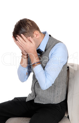 Man sitting in a vest holding hands over face