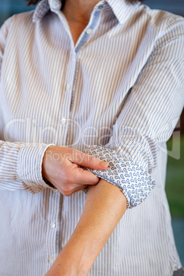 Woman is rolling up sleeves of her blouse