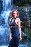Junge Frau steht vor einem Wasserfall